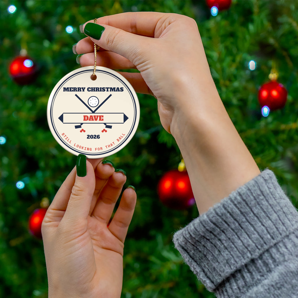Personalized golf ornament held up in front of a Christmas tree