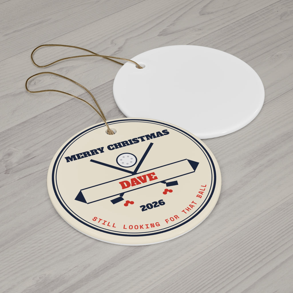 Round ceramic golf Christmas ornament with gold string on a wood table
